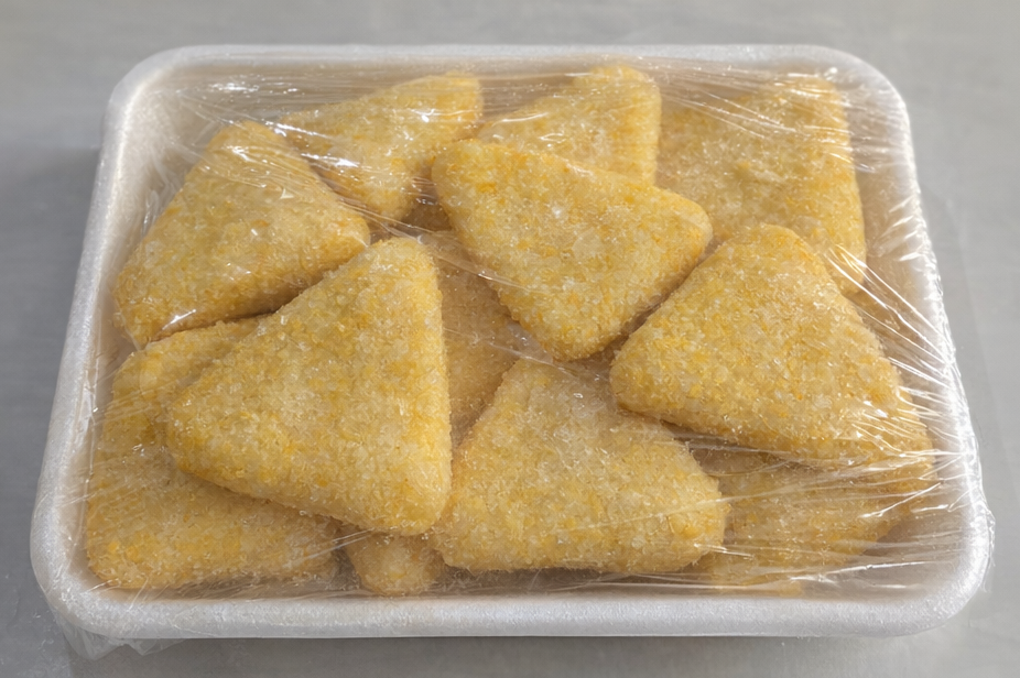 Tray of triangular yellow snacks wrapped in plastic on a white surface